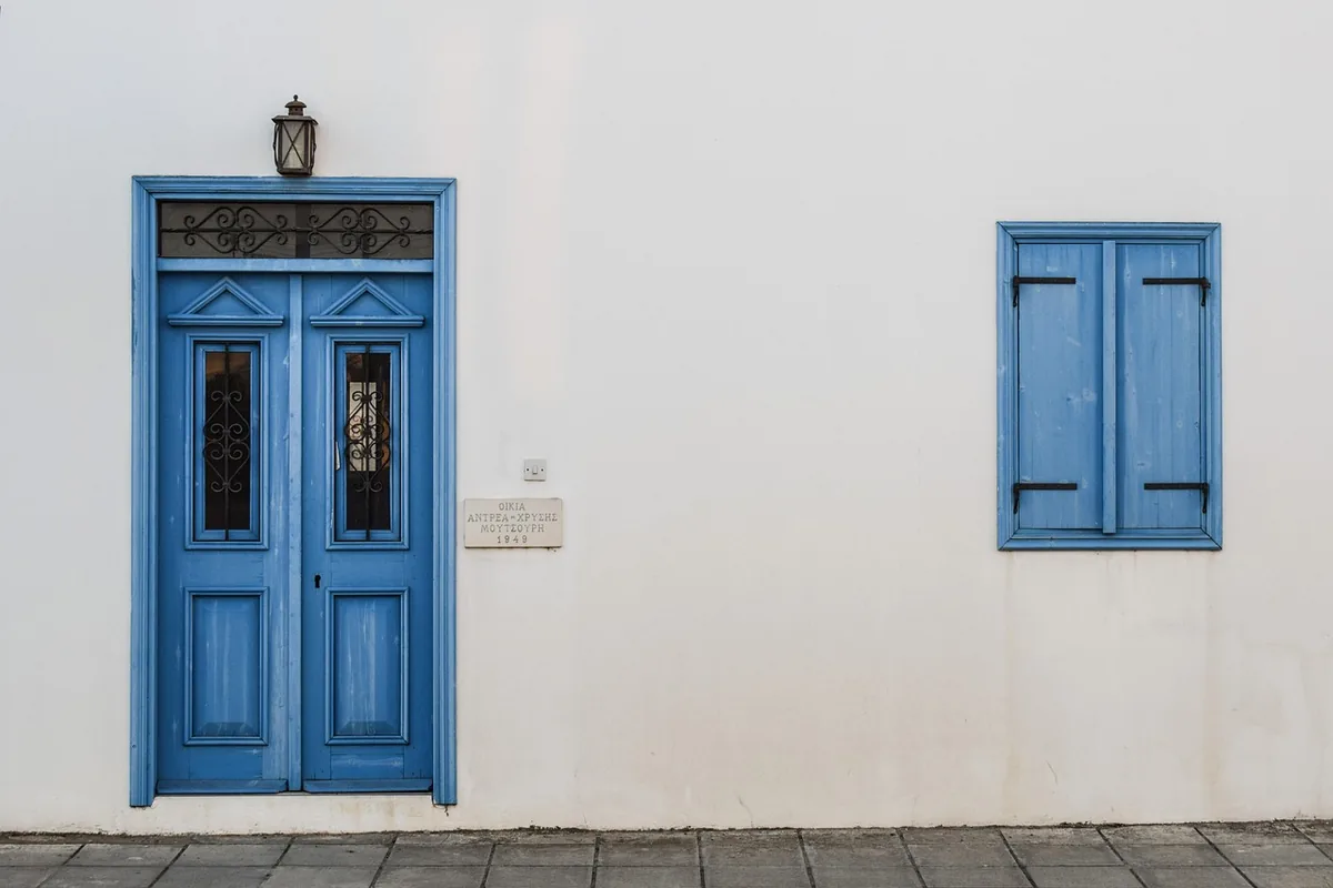 Puerta y contraventanas de madera azul en una fachada encalada, vistas de frente