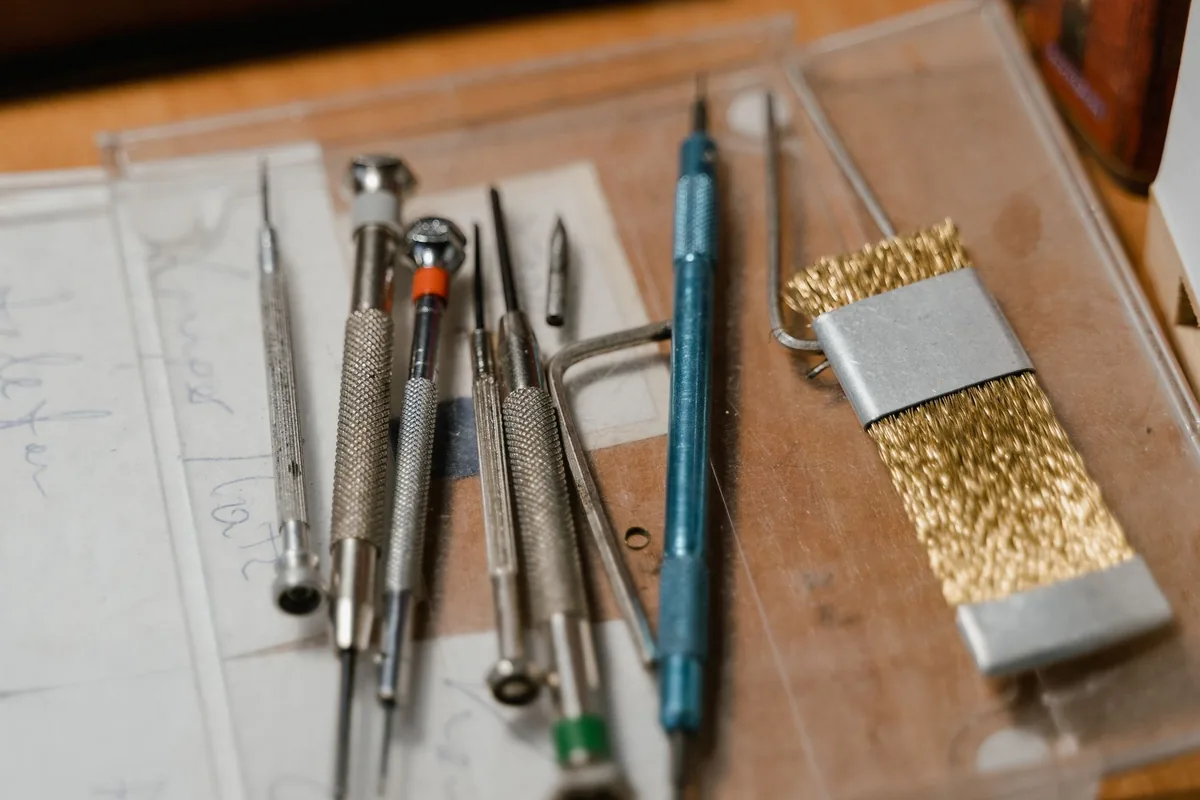 Destornilladores de precisión, una llave y un cepillo de latón sobre una mesa de trabajo