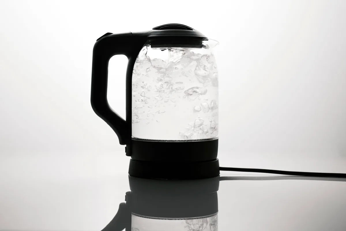 Hervidor eléctrico de cristal con el agua hirviendo
