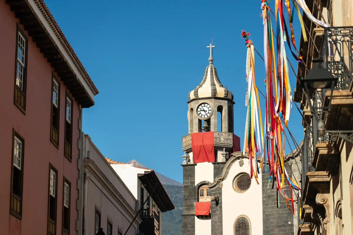 Calle histórica de Tenerife con balcones de madera y una torre de iglesia al fondo