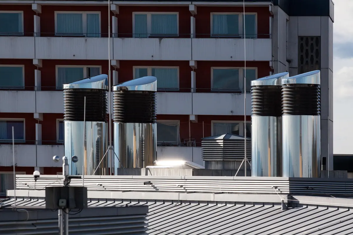 Chimeneas de extracción de acero inoxidable sobre la cubierta de un edificio con balcones