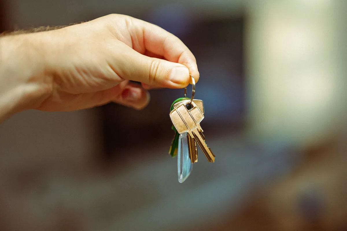 Mano que sostiene un manojo de llaves de vivienda con un llavero transparente